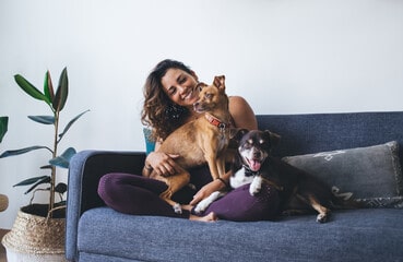 Happy white woman resting with her dog on sofa at home